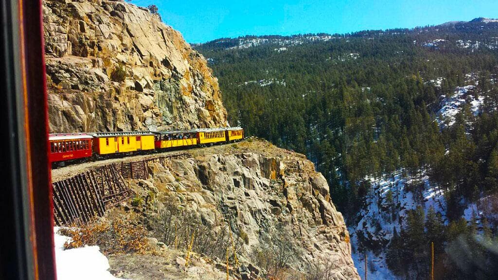 Heritage train traversing dramatic cliffside route in mountain canyon