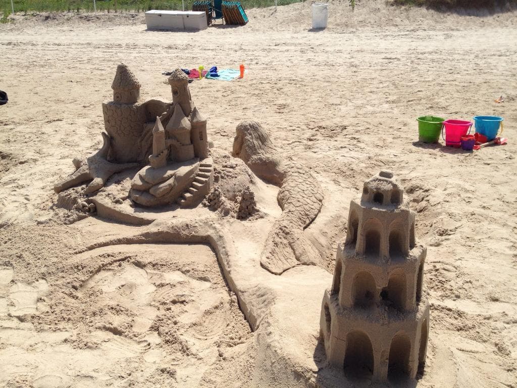 Elaborate sandcastle turrets and moats on family beach