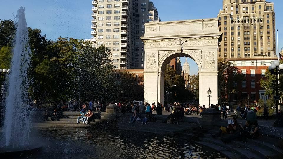Visitors enjoying fountain and Washington Square Arch in NYC