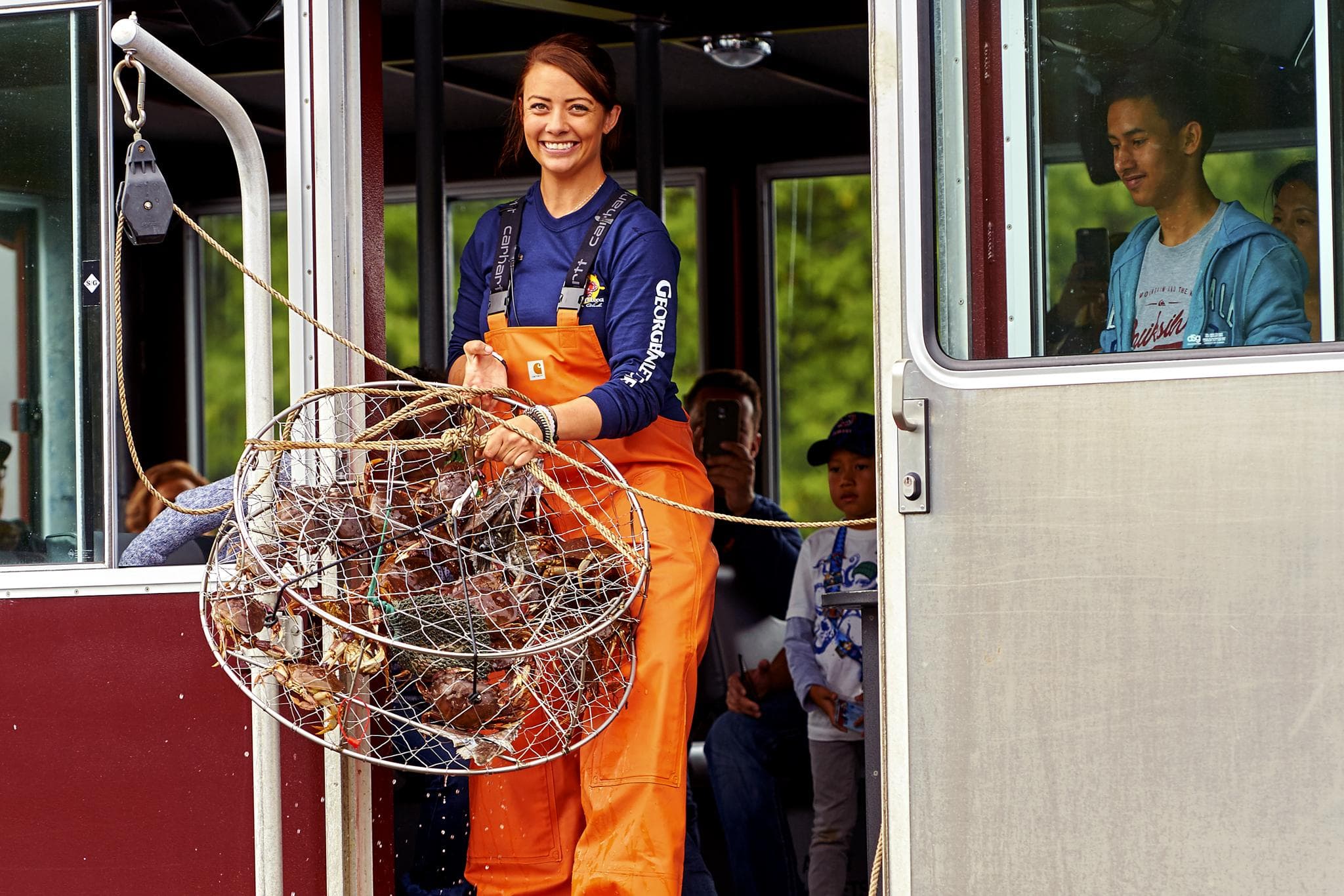 Crew member holding crab pots aboard fishing boat in Alaska